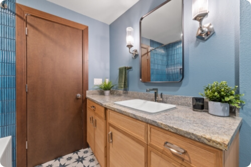 A modern bathroom featuring a wooden cabinet, blue walls, and stylish fixtures.